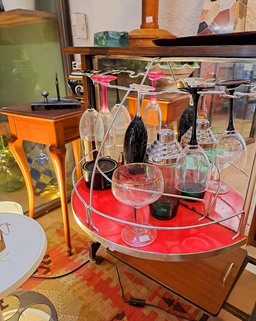 Carro de begudes vintage amb copes penjades i una coctelera